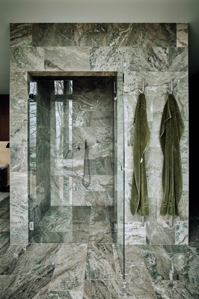 Bathroom area with green Swedish marble, towels and glass shower compartment